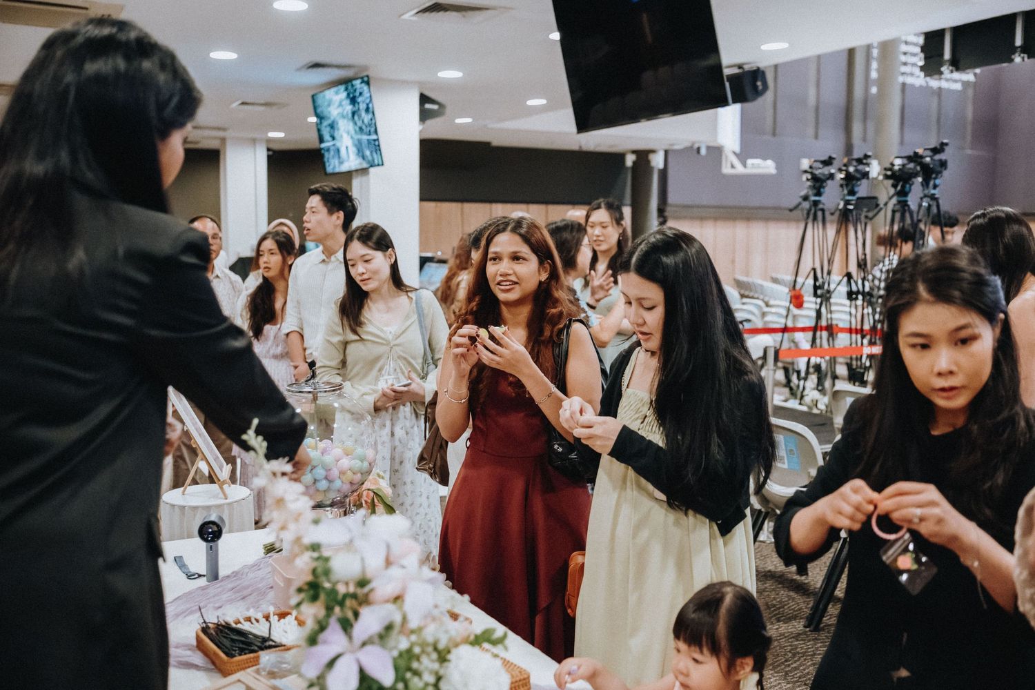 Wedding guests mingling and taking photos at a reception with decorated tables.