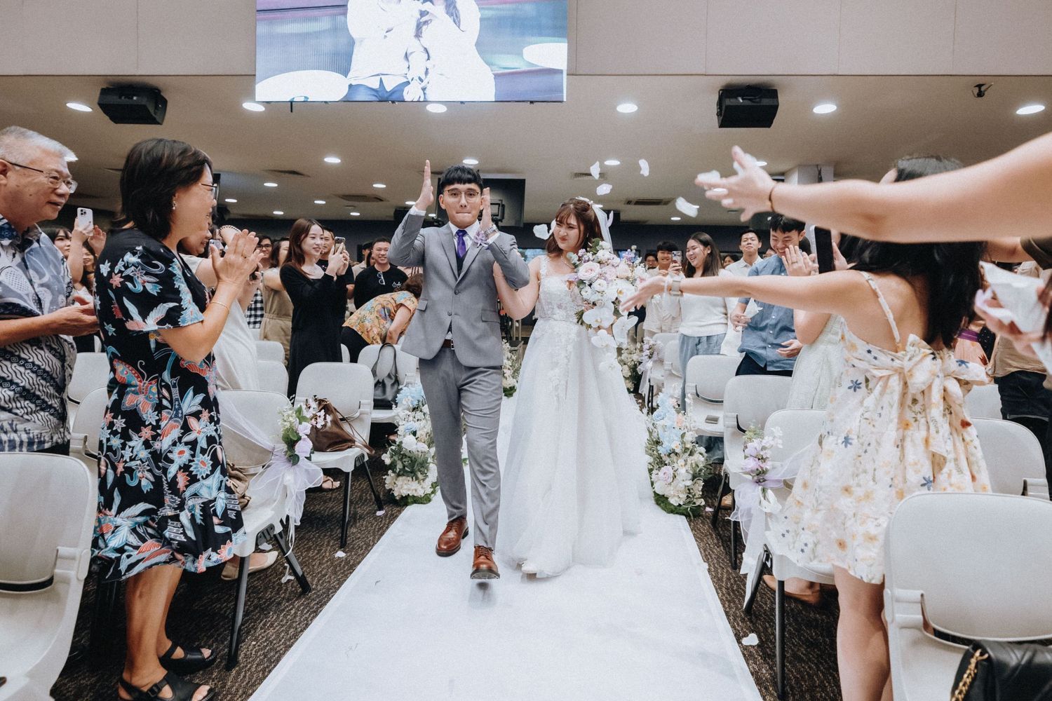 Wedding reception venue with white table settings and guests celebrating in a modern banquet hall.