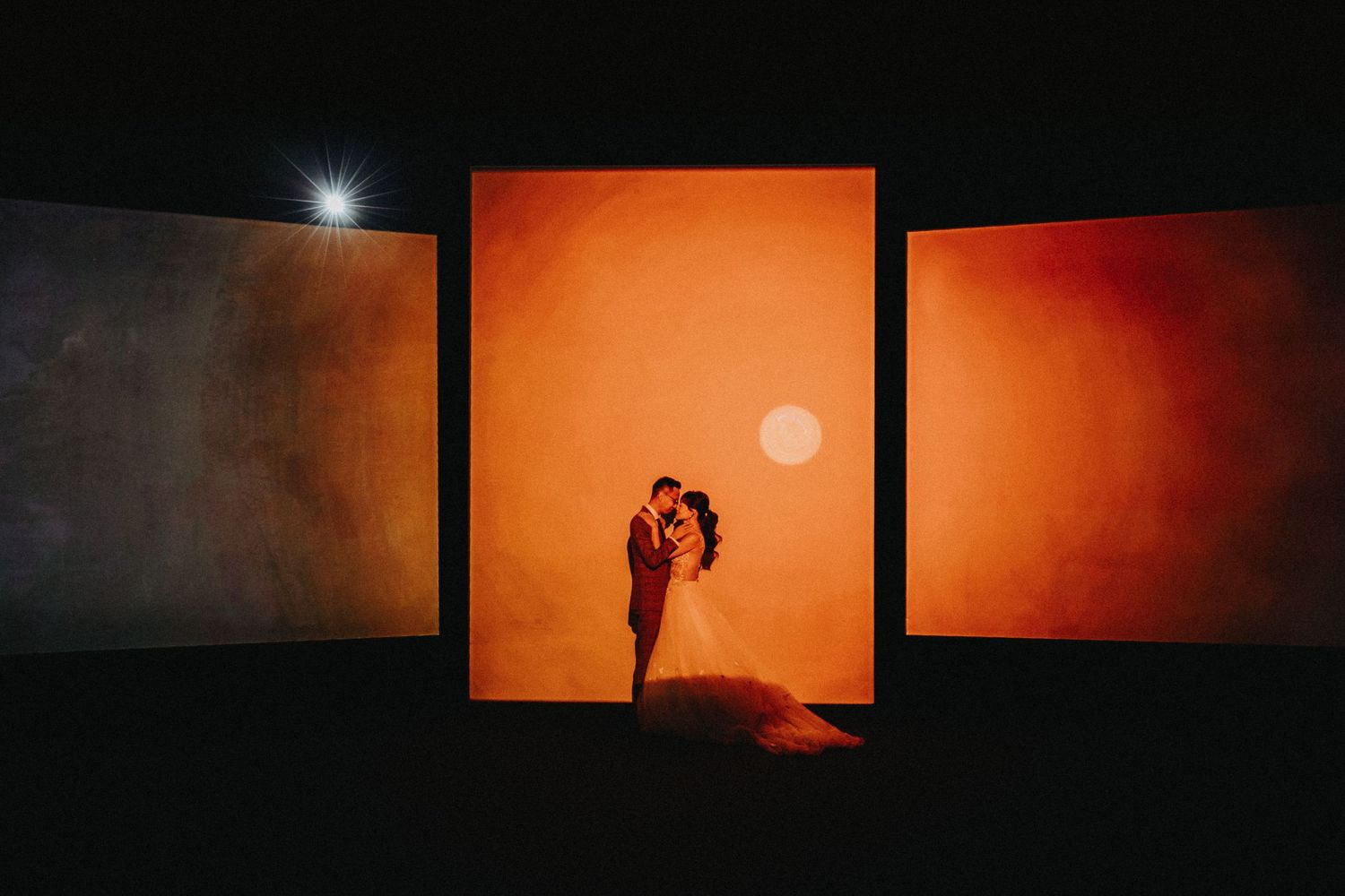 A dramatic silhouette photograph against an orange sunset backdrop with dark frames on either side.
