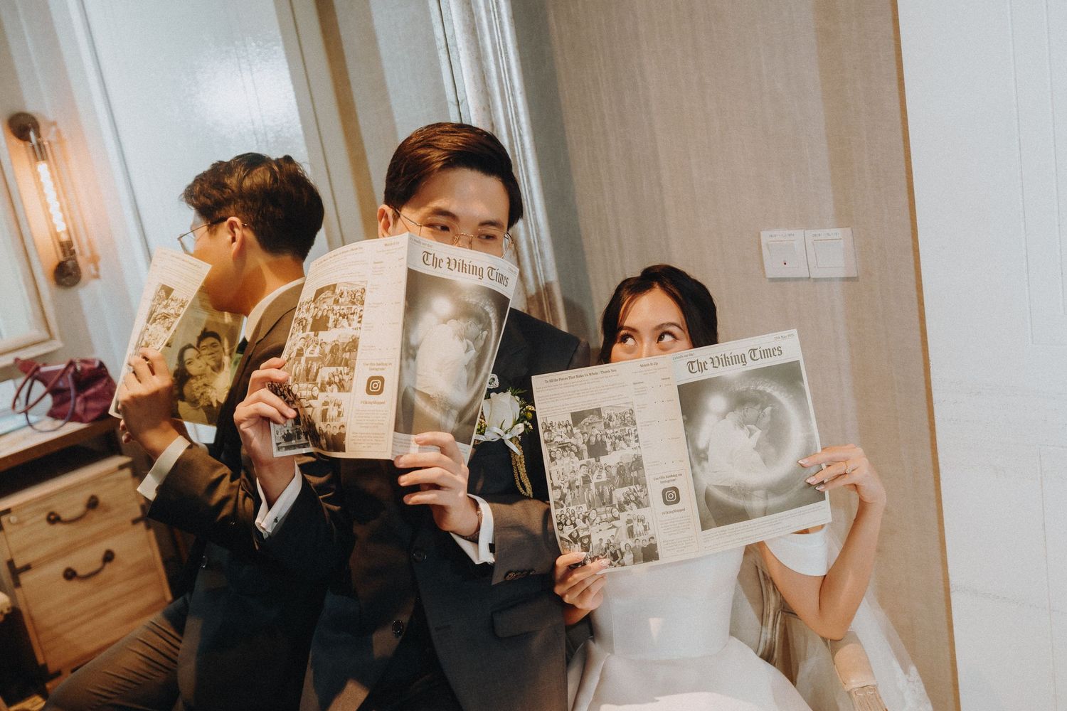 Wedding guests hold up vintage photographs during a reception celebration.