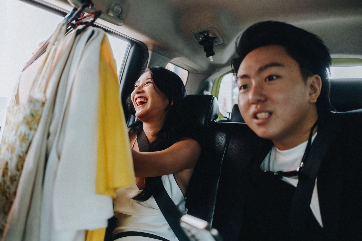 People sharing a joyful moment inside a car with a surfboard visible.