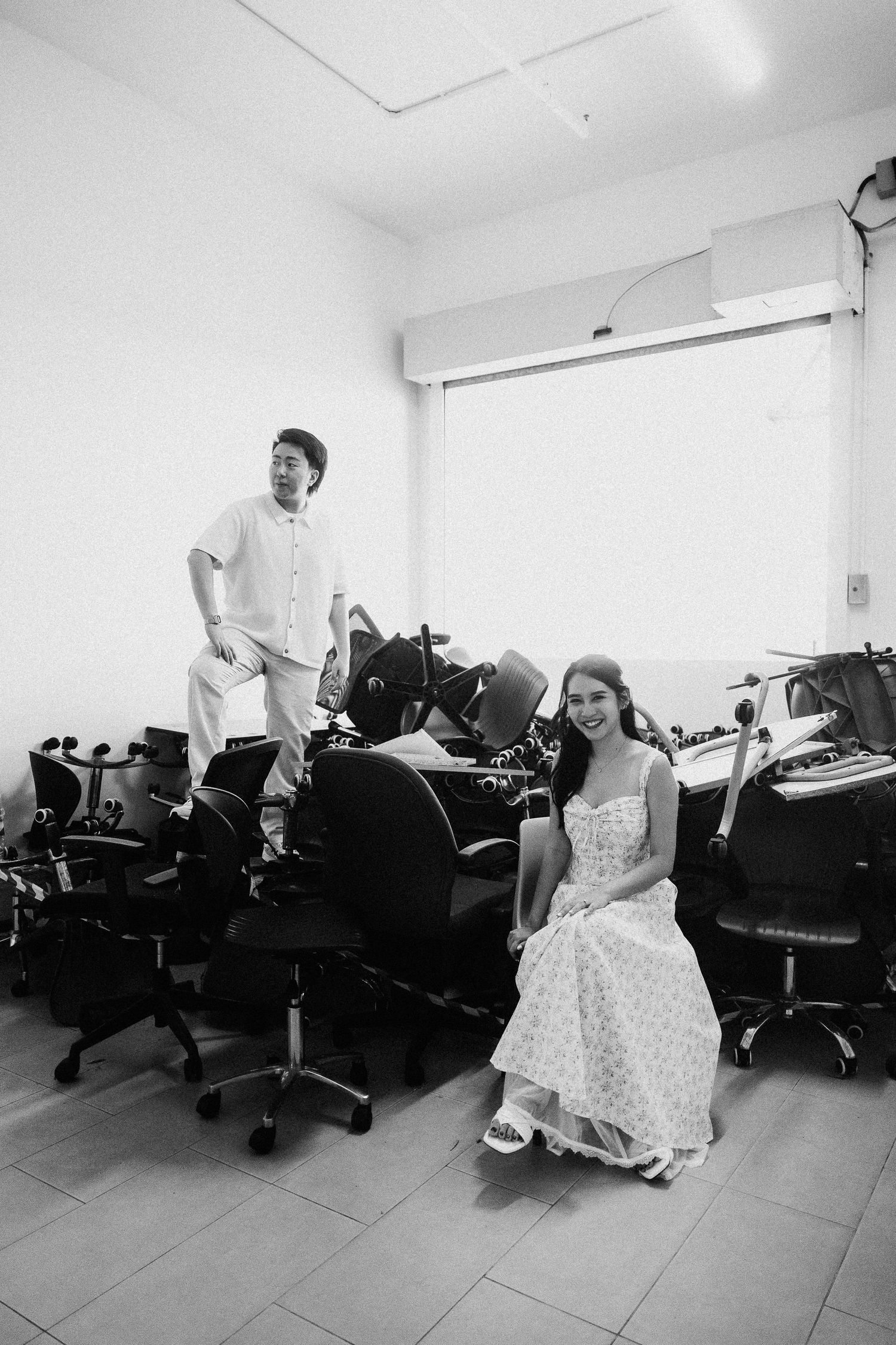 Black and white photo of a couple dancing playfully in an office space.