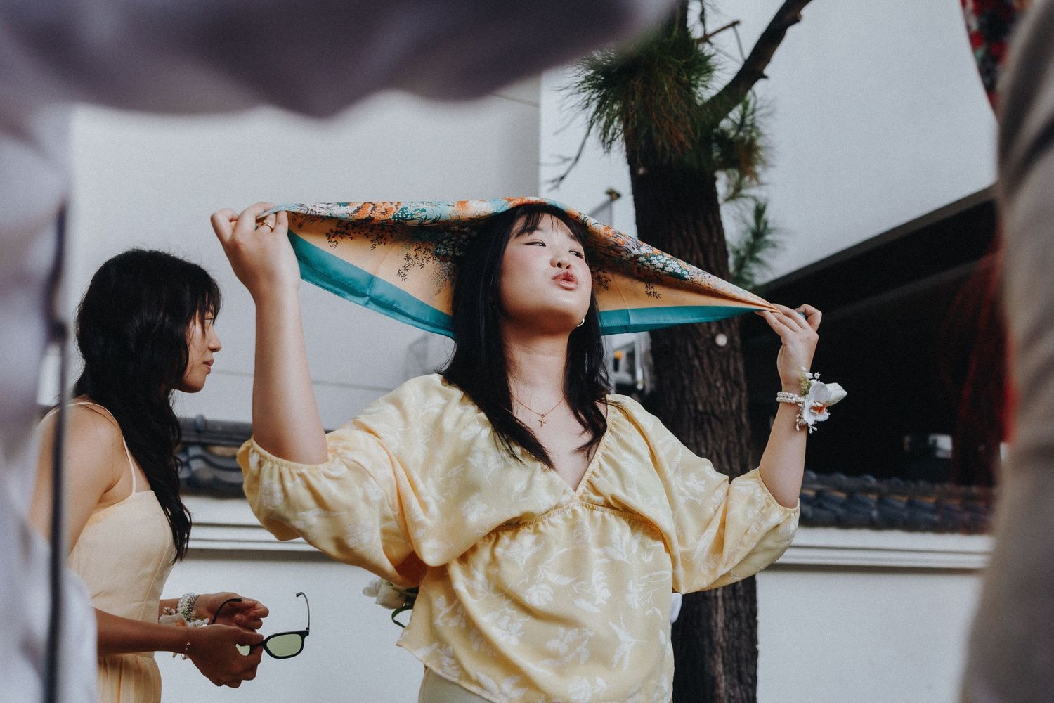 Person in yellow silk blouse dancing enthusiastically at an outdoor party.