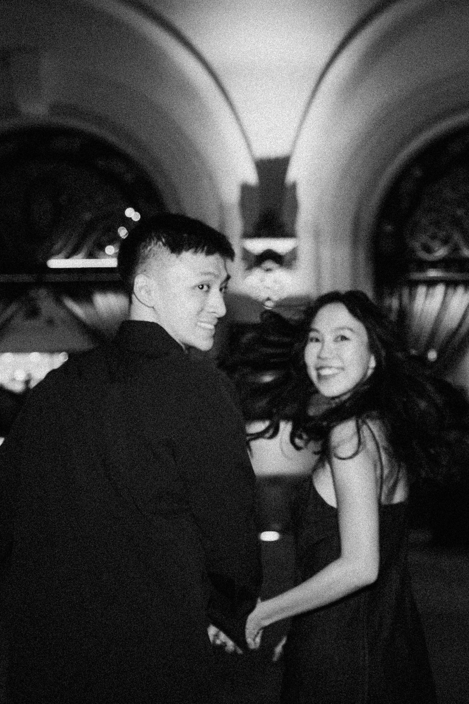 Couple sharing a joyful moment together in an elegant venue with arched ceilings.