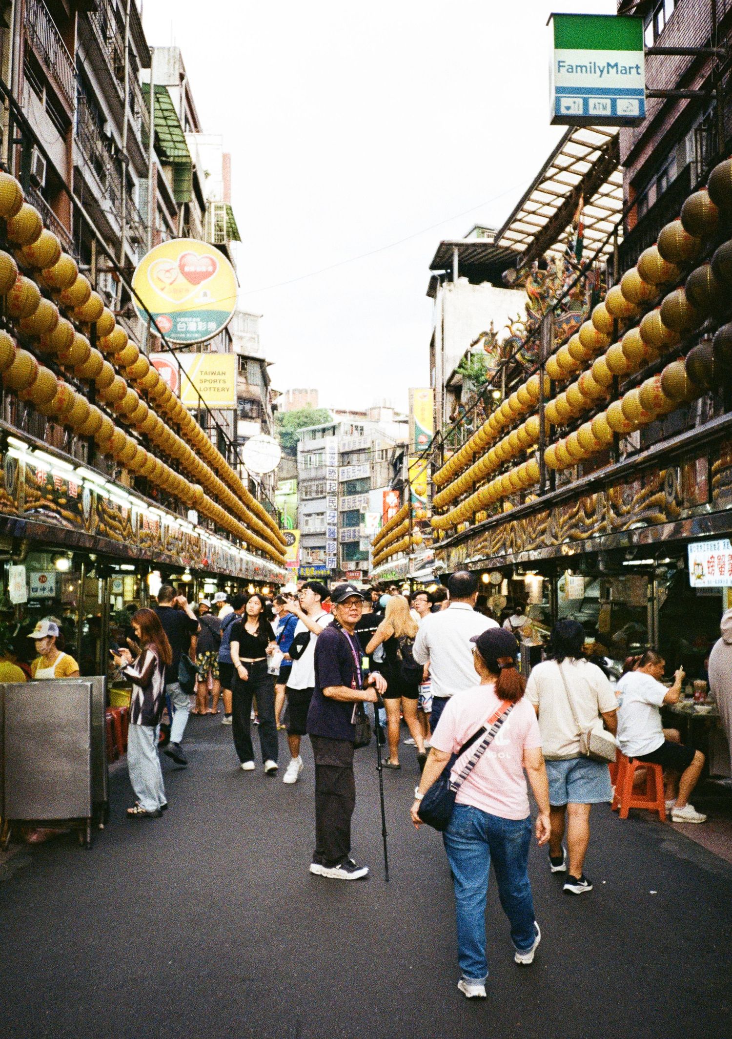 Traditional Asian market street lined with hanging yellow lanterns stretching into the distance.