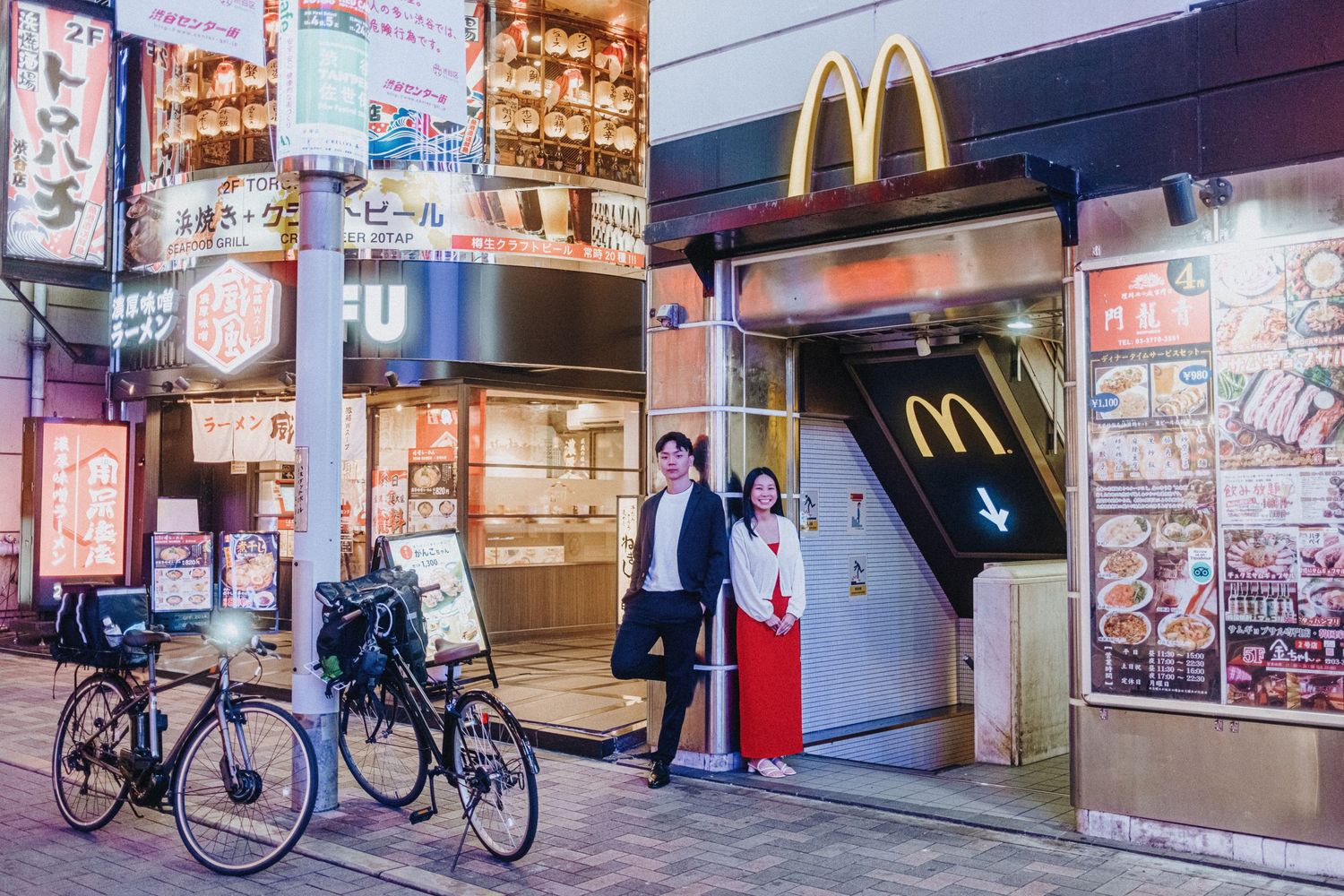 Row of illuminated McDonald's restaurant storefronts and bicycle parking in Japan.