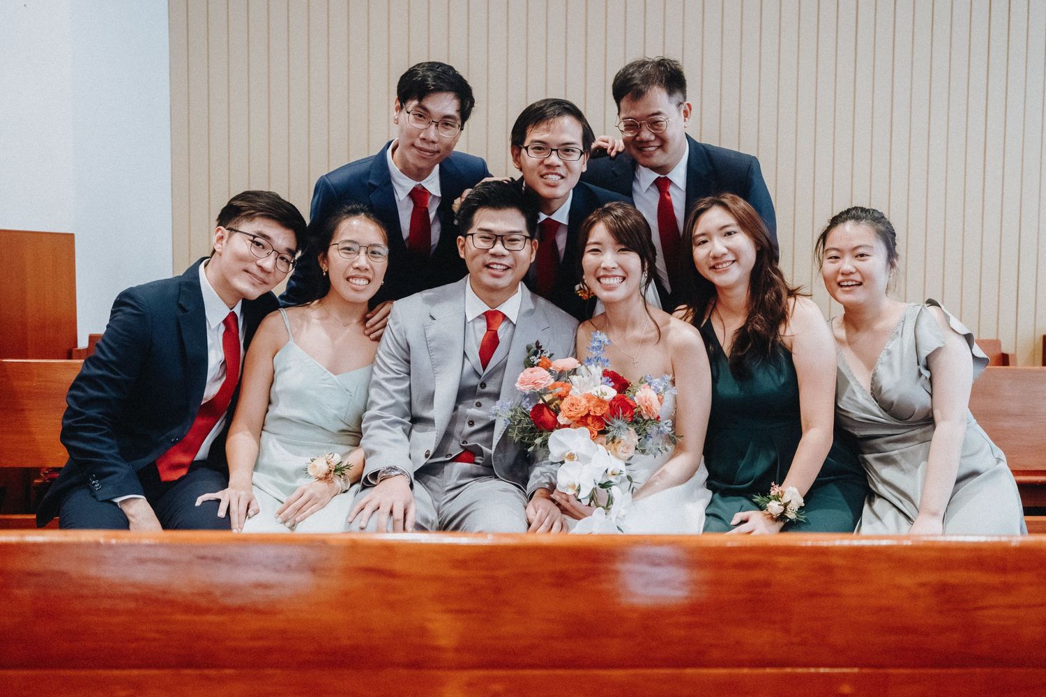 Wedding party members pose together on church pews for group photos.