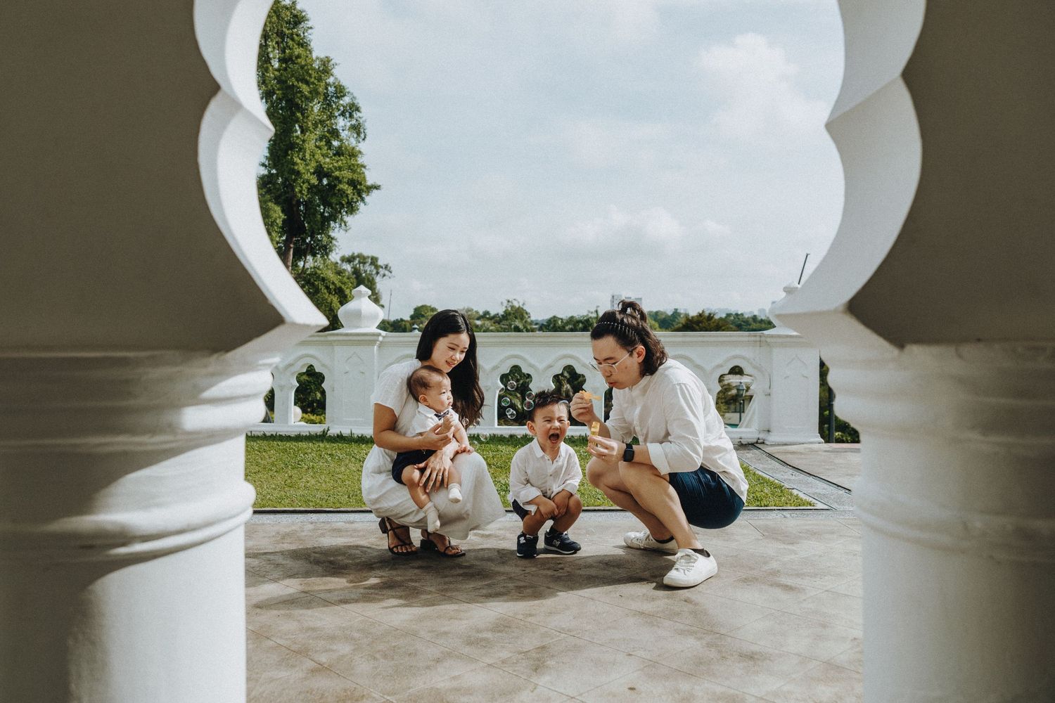 Couple shares romantic moment under white arched colonnade at outdoor venue during wedding celebration.