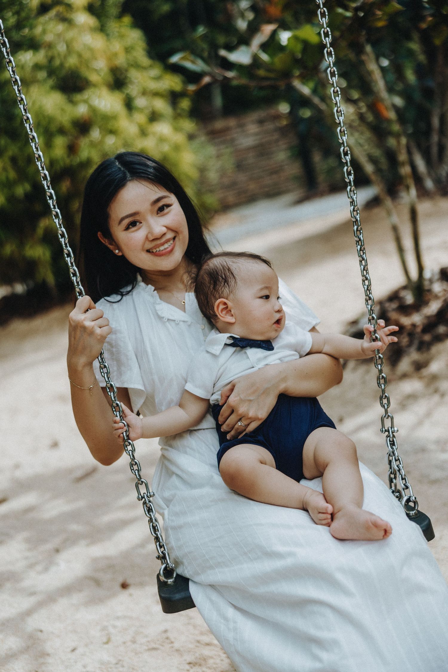 Parent and young child share a joyful moment together while sitting on an outdoor swing in a peaceful garden setting.