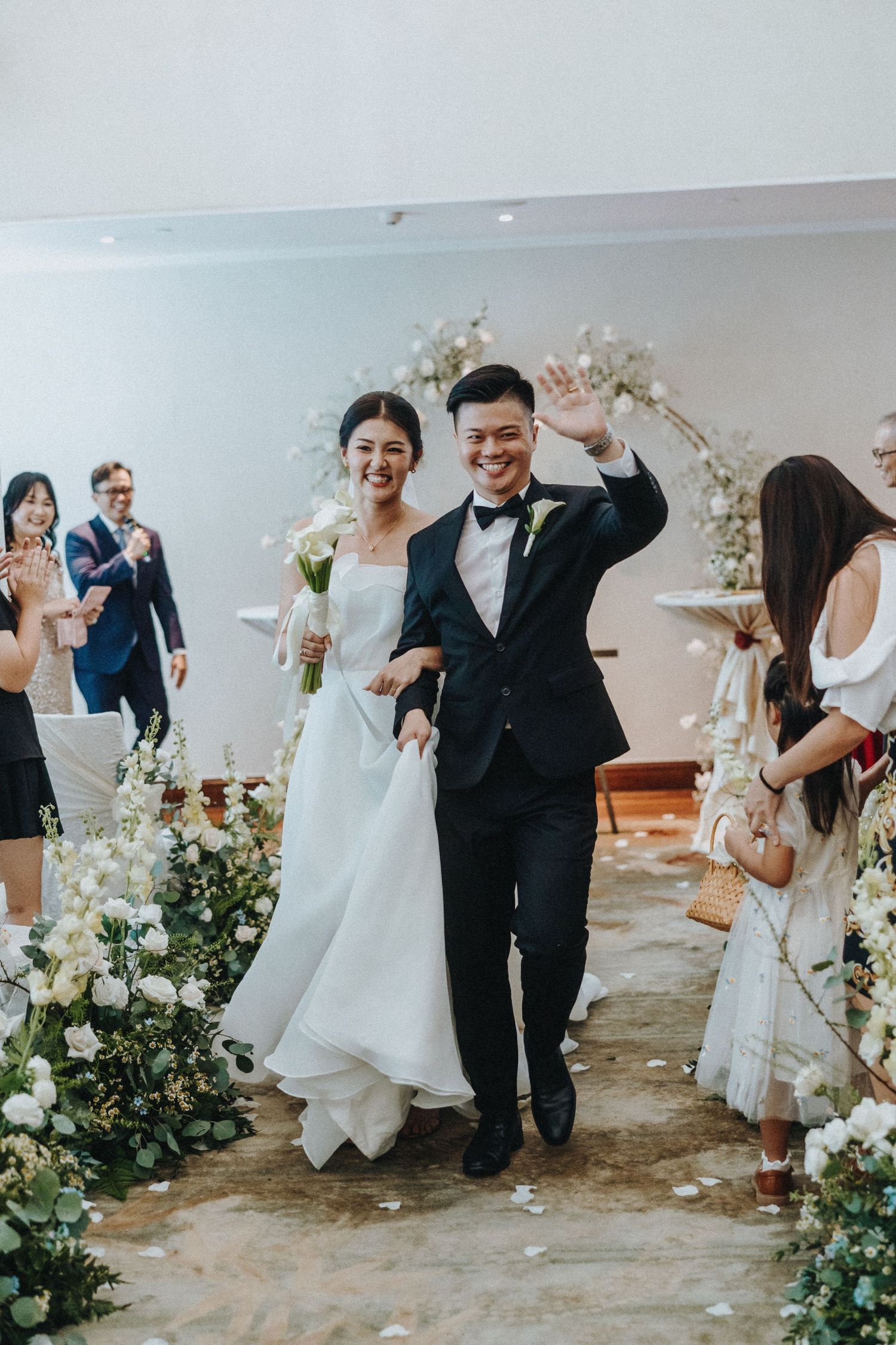 A joyous wedding ceremony exit along a flower-lined aisle with guests celebrating.