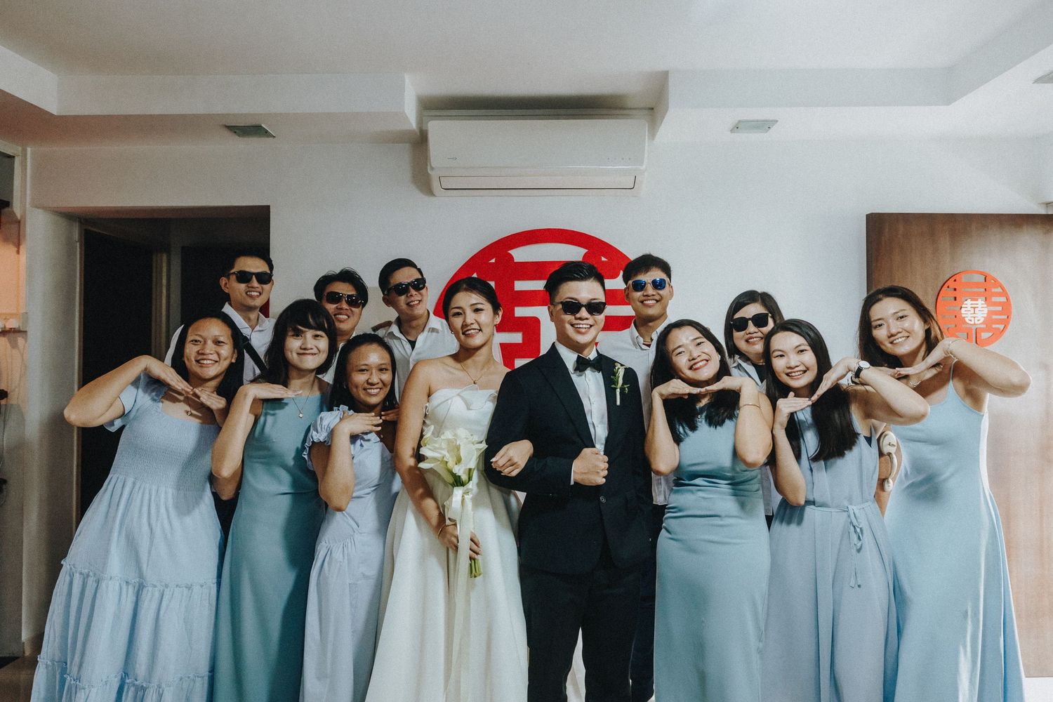 Wedding party in light blue bridesmaid dresses posing together in a group photo with fun expressions.