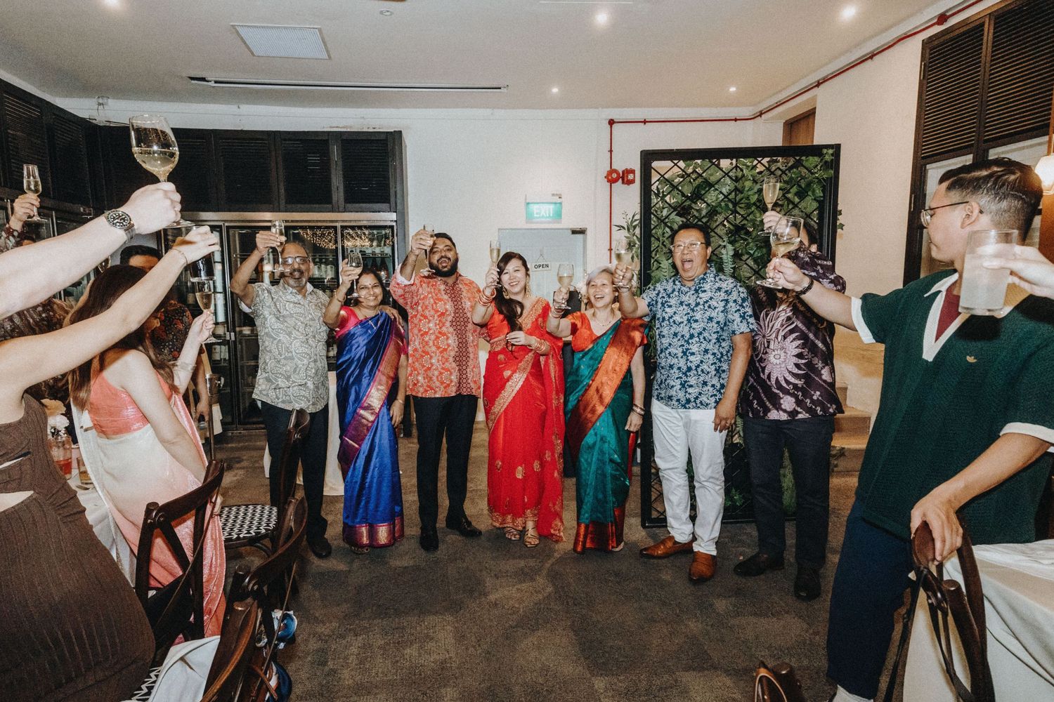 Wedding party raises glasses in a toast during a celebratory indoor reception gathering.