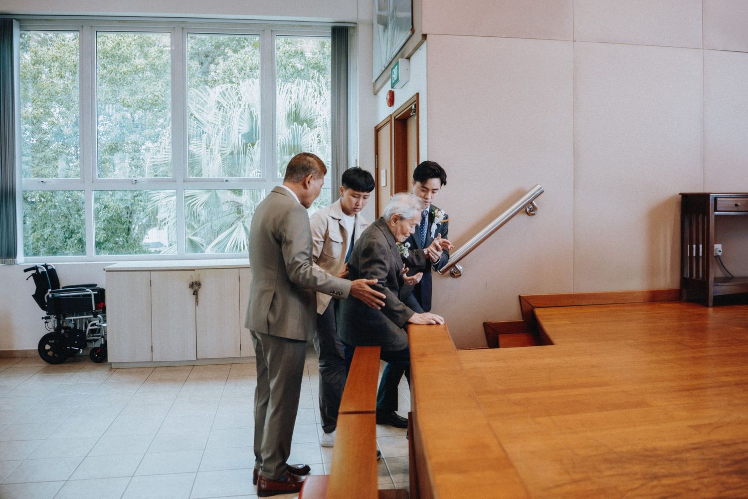 Formally dressed men reviewing documents at church reception desk before wedding ceremony.