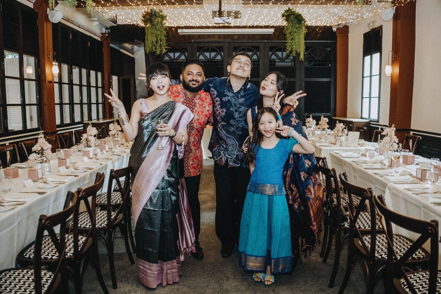 A joyful group of five poses playfully in a decorated wedding reception dining room.