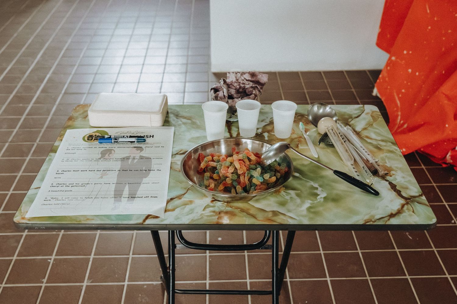 A messy cafeteria table with leftover food scraps, dishes, and utensils on disposable plates and trays.
