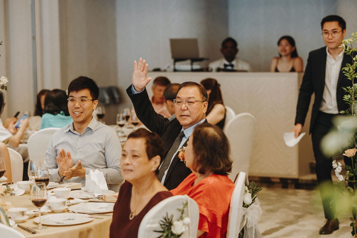 Wedding guests seated at decorated tables during an indoor reception celebration.