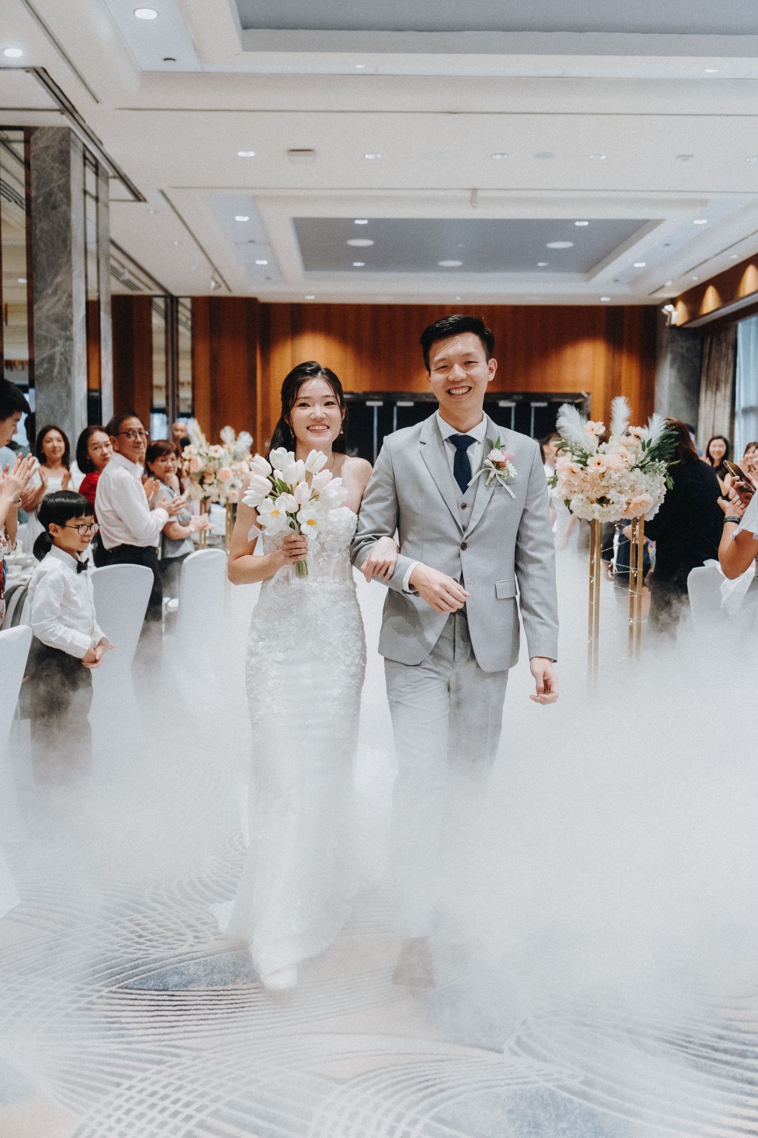 Elegant wedding entrance with dramatic fog effect and florals in luxury venue.