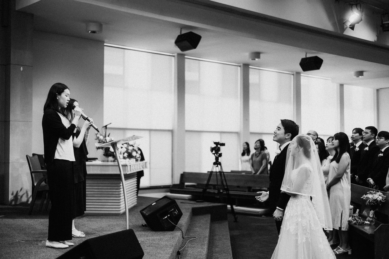 Indoor church wedding ceremony with dramatic lighting and floral decorations.