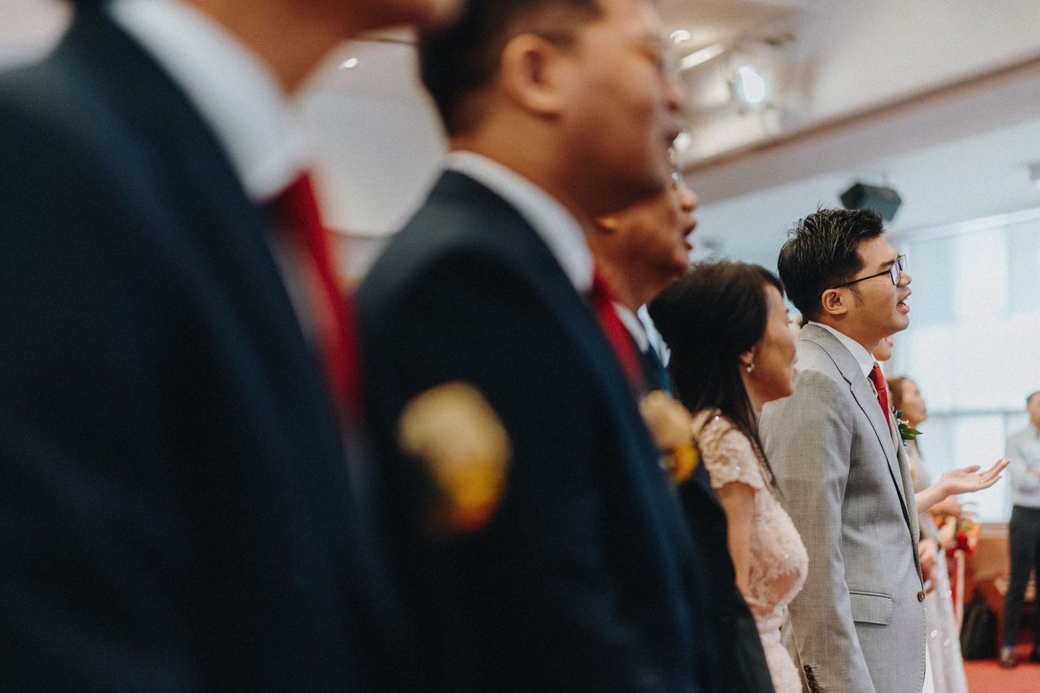 Wedding attendees stand together during a ceremony in formal attire.