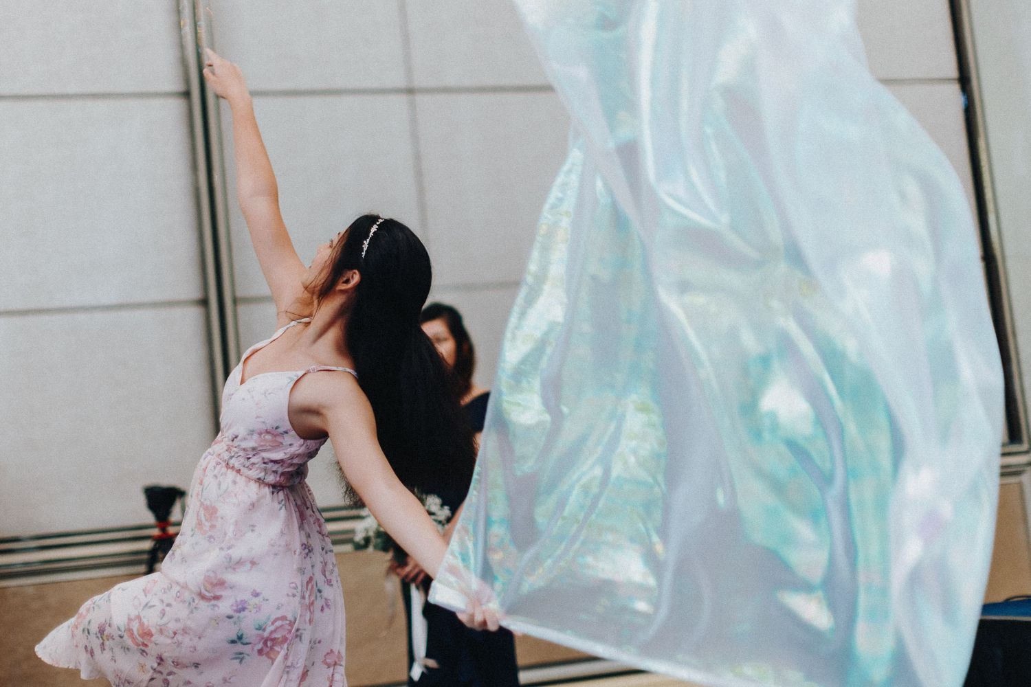 Wedding couple playfully posing with flowing veil in front of glass windows.