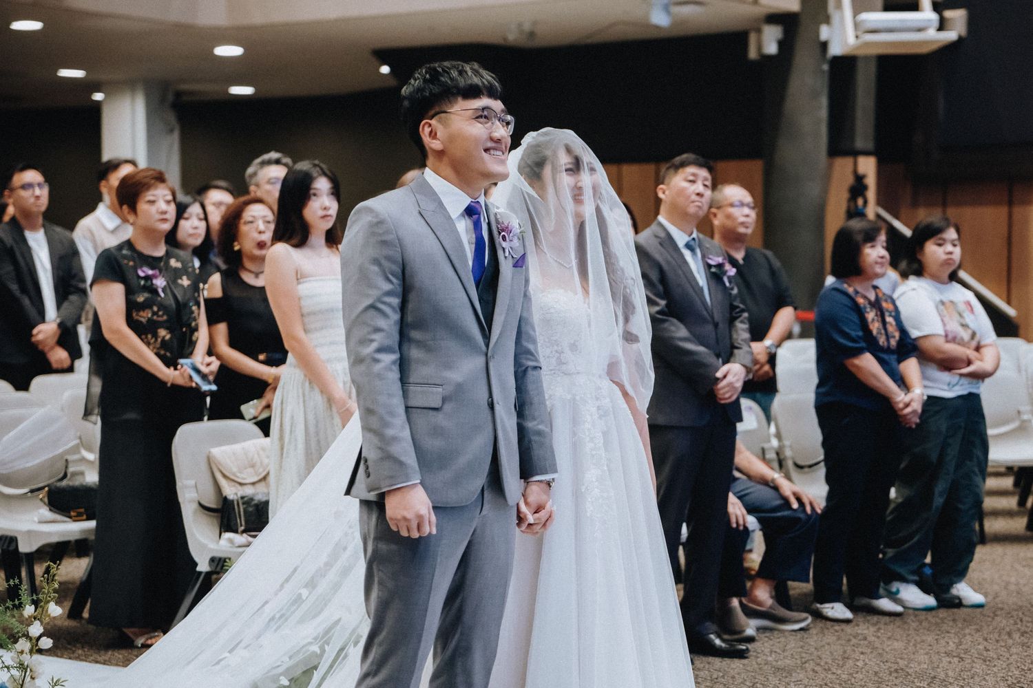 Wedding ceremony in progress with couple at altar surrounded by guests.