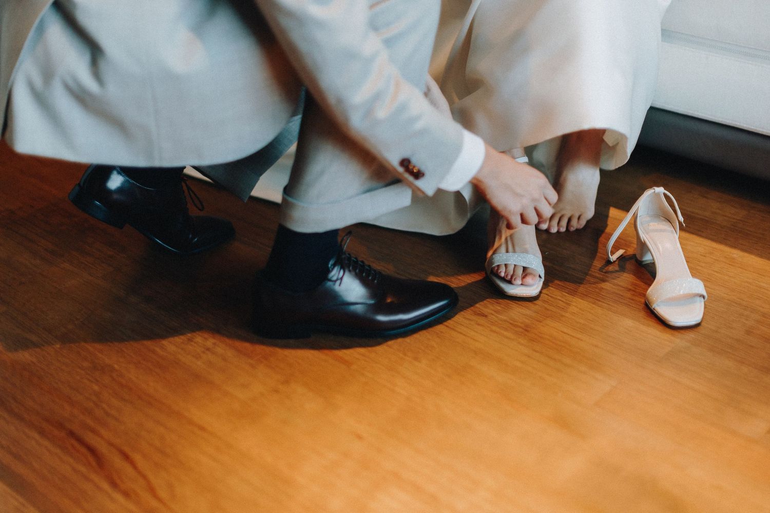 Detail shot of wedding shoes and formal attire on hardwood floor.