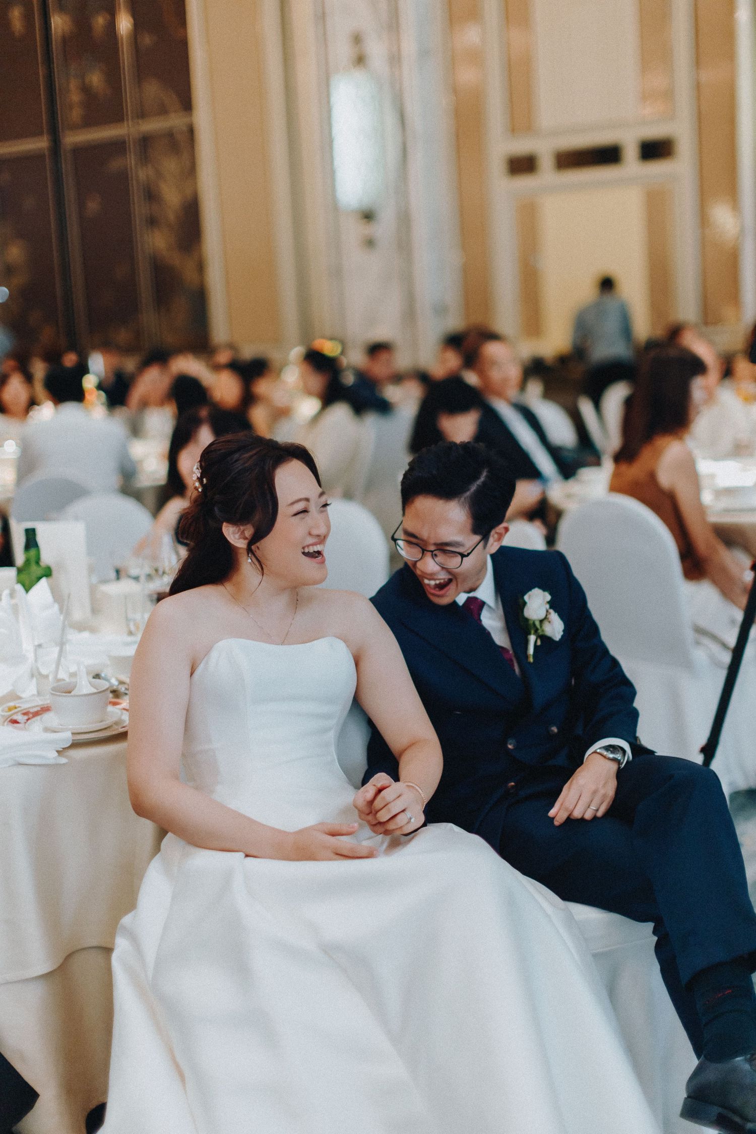 Wedding reception scene in an elegant ballroom with white table settings and joyful moments.