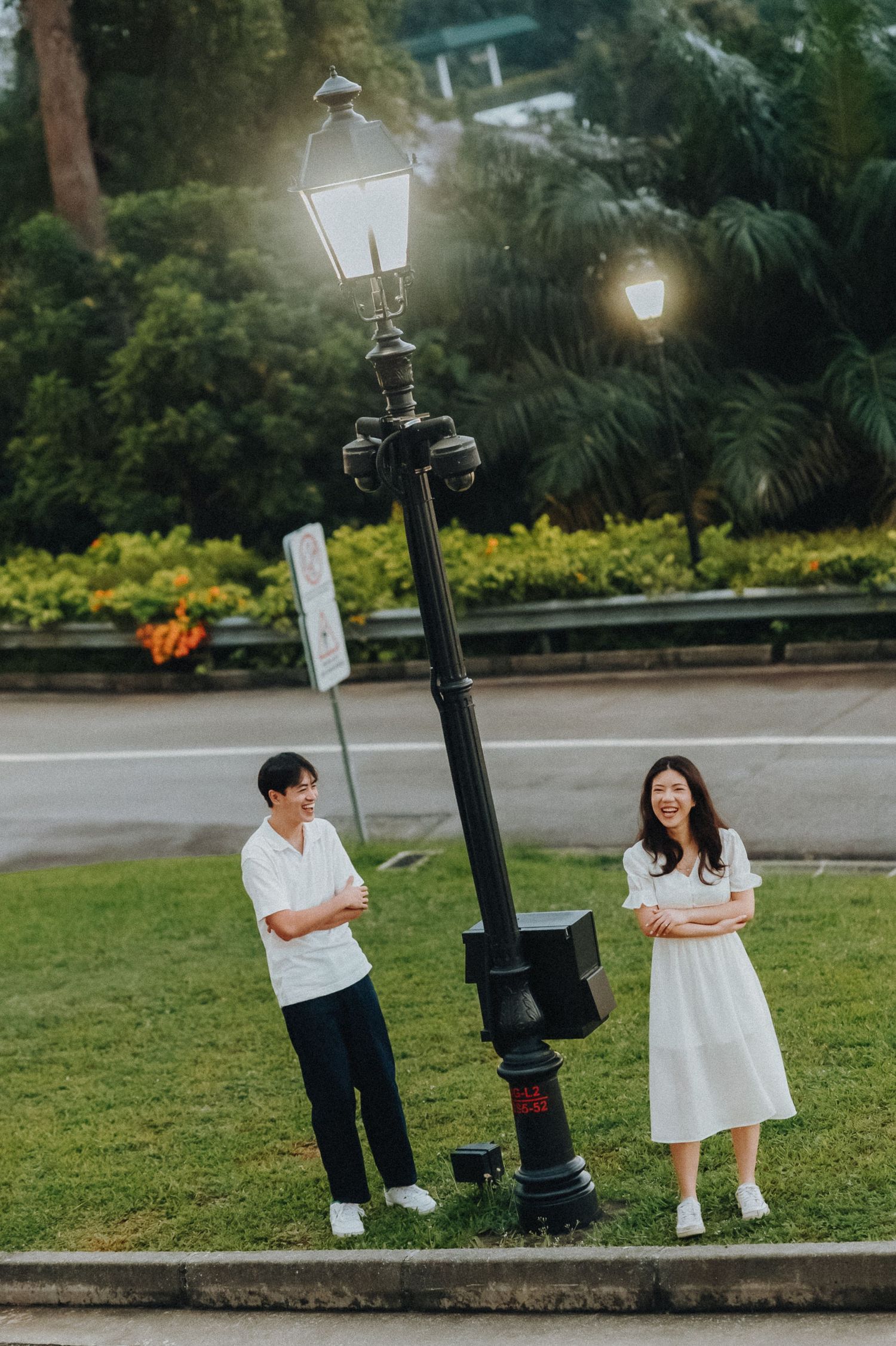 Couple posing by vintage street lamp post in park during daytime.