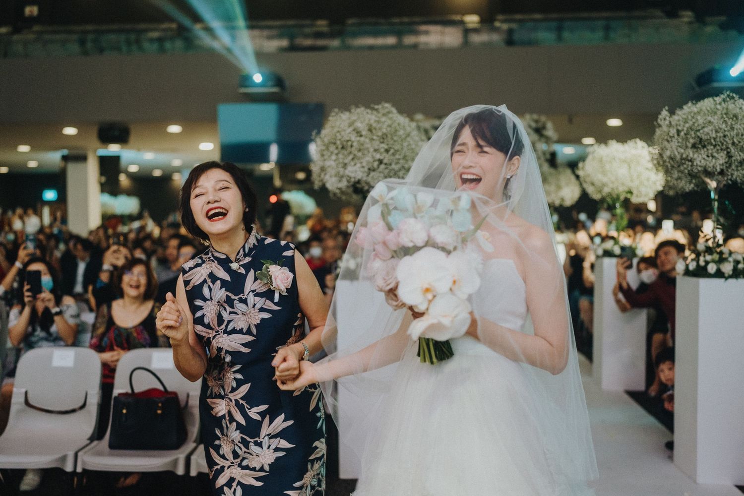 A joyous wedding ceremony moment with a bride in white holding a bouquet among celebration decorations.