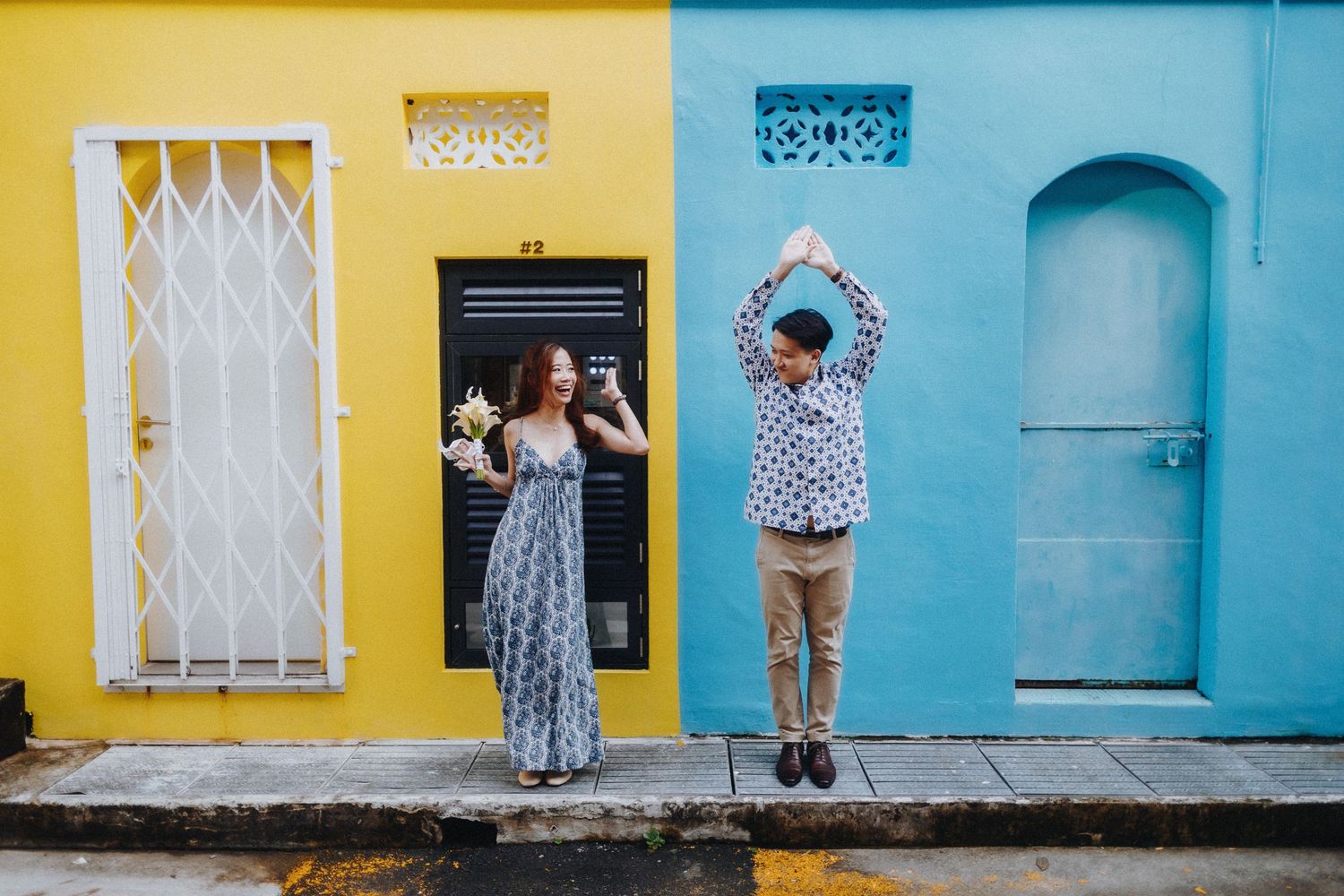 Colorful street with alternating yellow and turquoise painted buildings featuring white doors and windows.