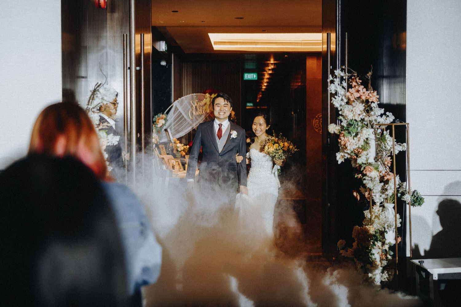 Wedding ceremony entrance with atmospheric fog and floral arch decorations.