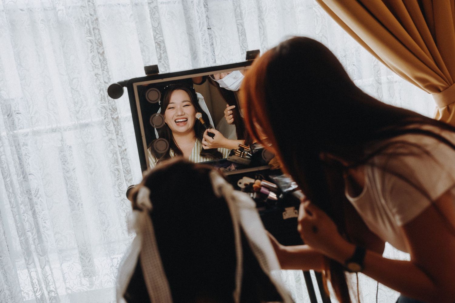 Behind the scenes photo of wedding preparation with makeup and mirror reflection.