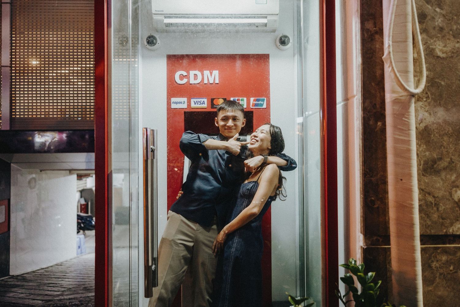 A romantic urban scene showing hands embracing against a red-tinted elevator backdrop.