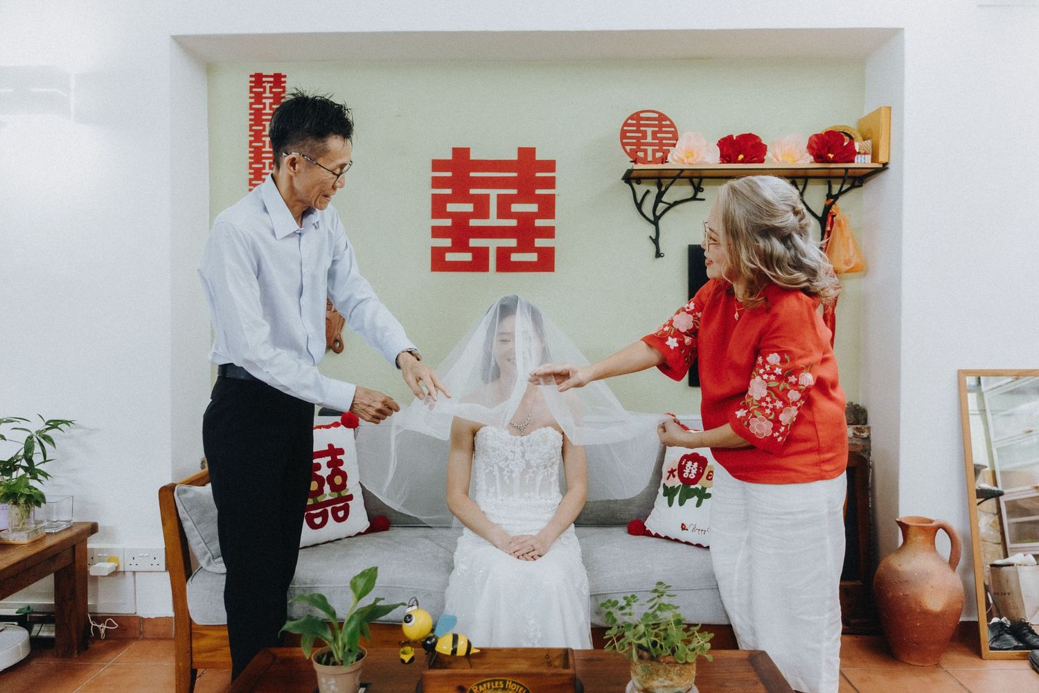 Traditional Chinese wedding tea ceremony scene with guests in white and red attire in a decorated room.