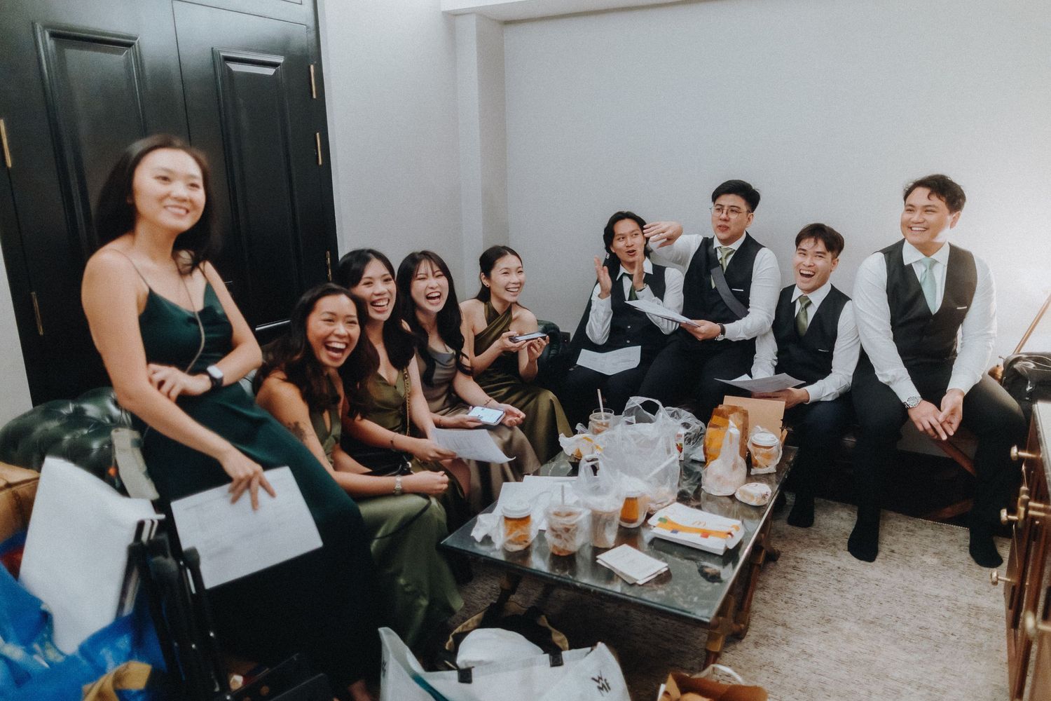 Group of performers relaxing backstage with beverages and snacks in a dressing room area.