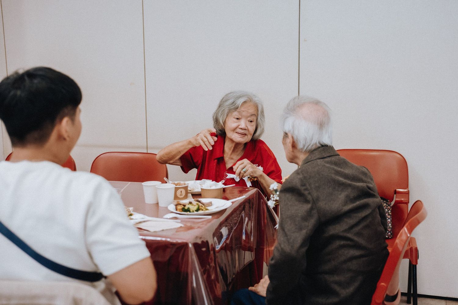 Elderly guests enjoy a meal together at a table during a wedding reception.