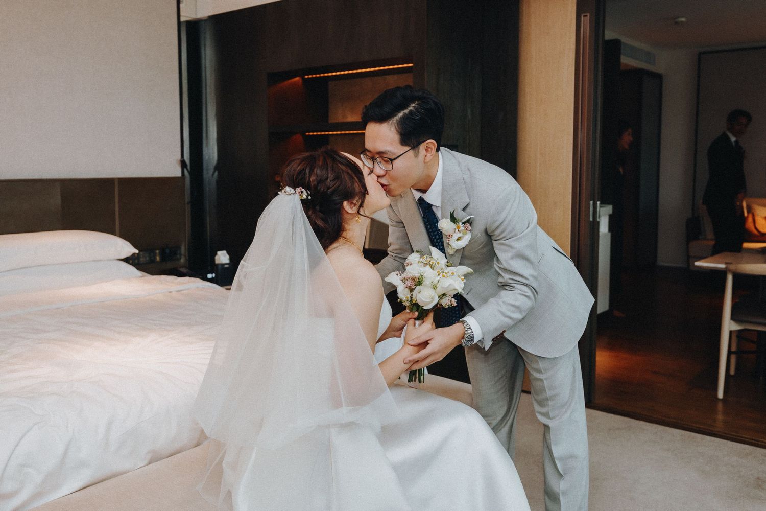 Bride and groom sharing intimate moments in a hotel room setting.