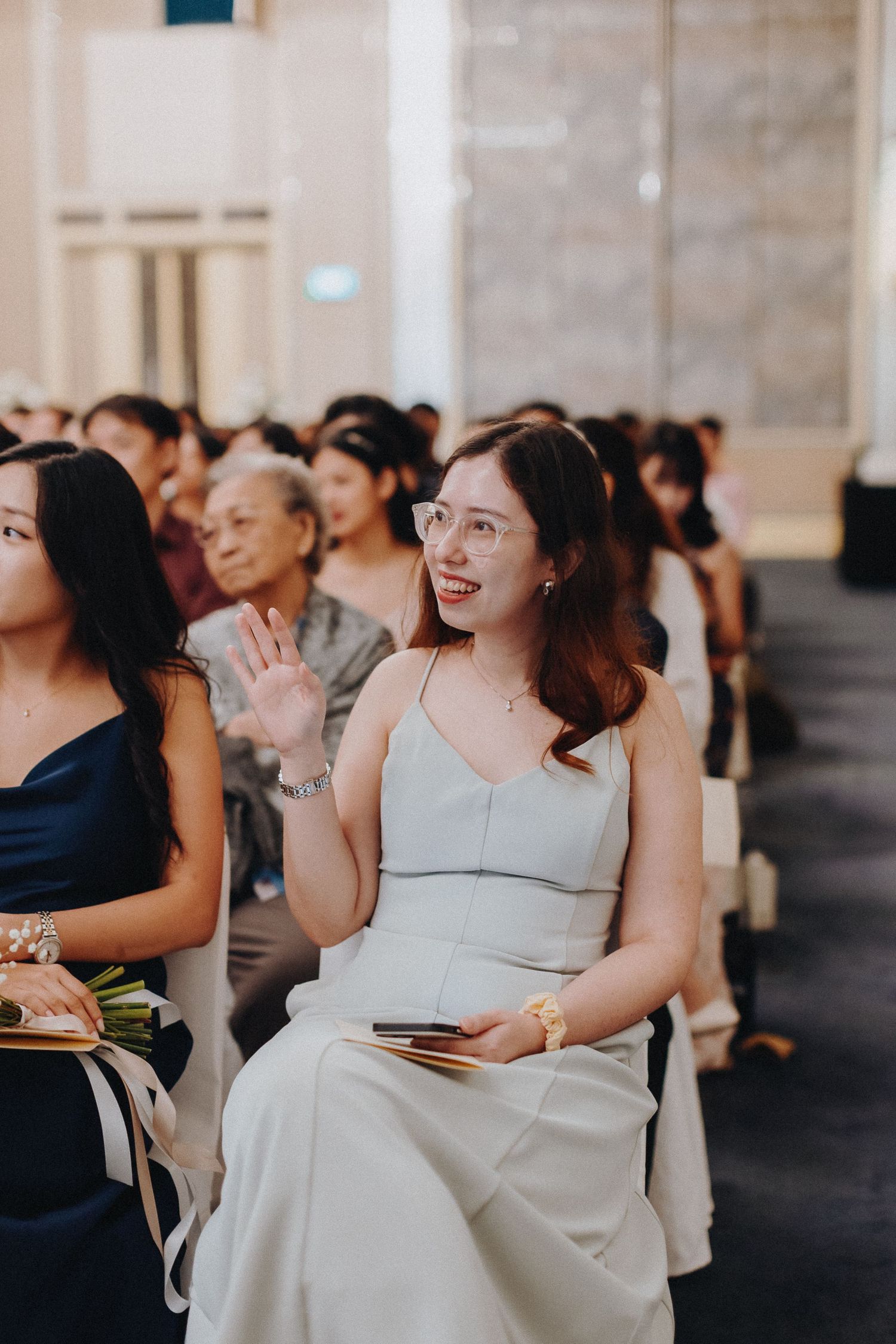 Wedding guests in formal attire smile and laugh during reception festivities.
