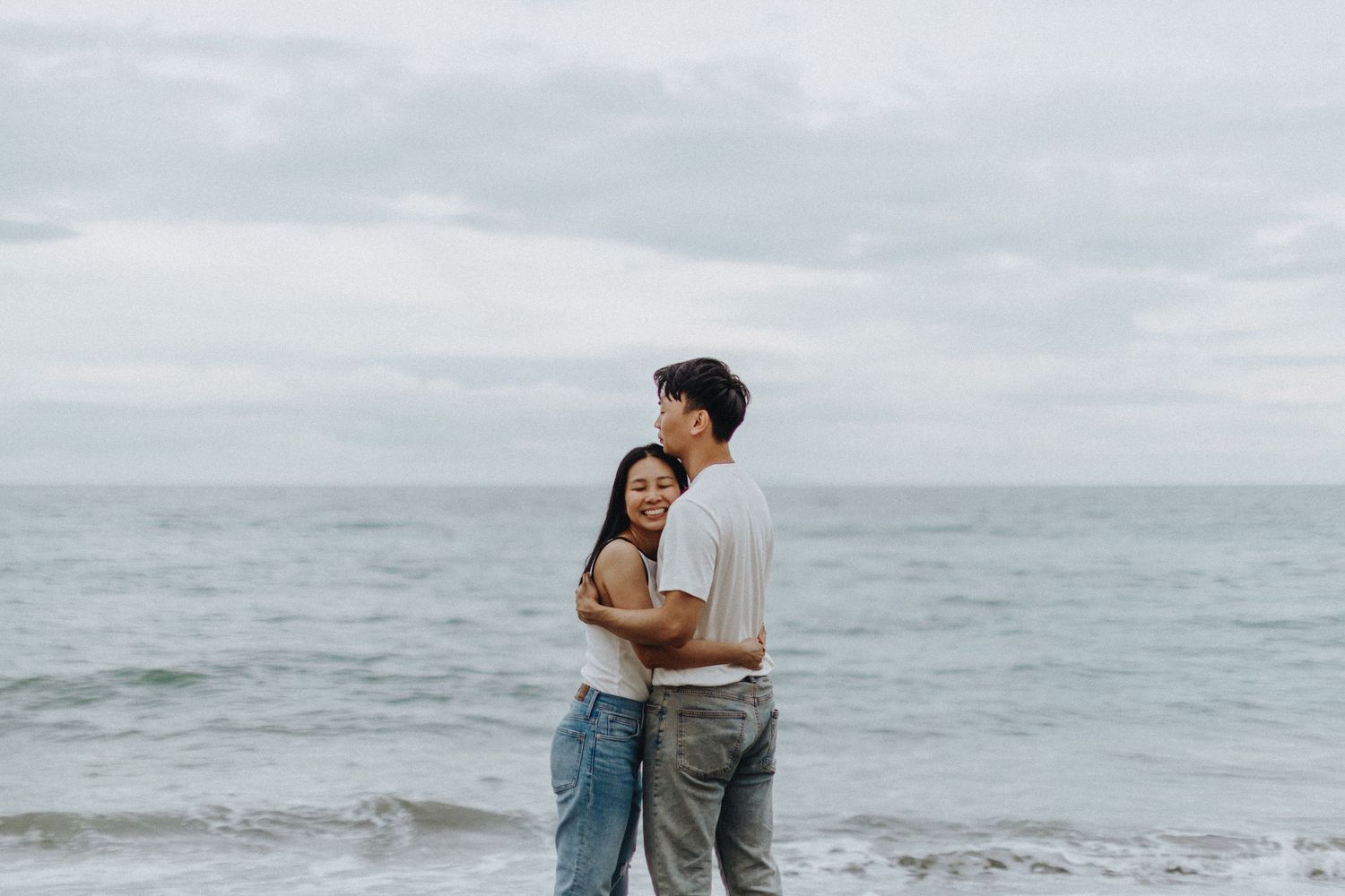 Scenic oceanside moment with waves crashing against rocky shore under cloudy skies.