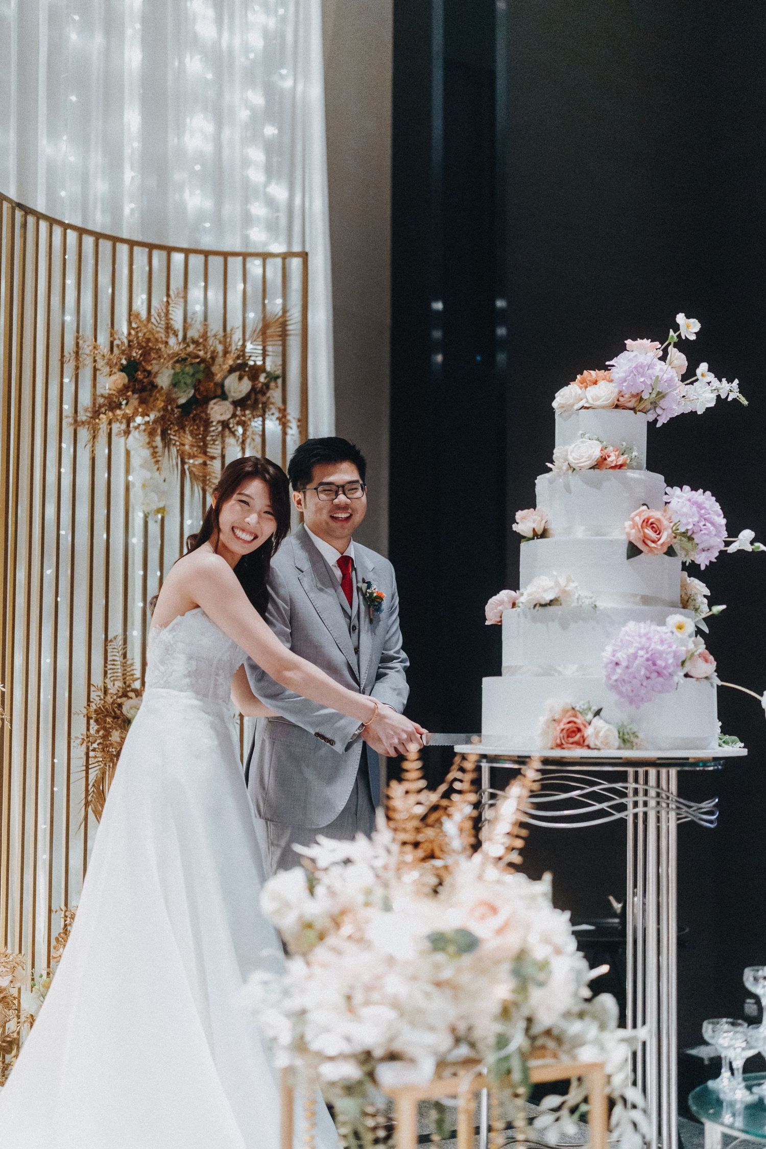 Wedding reception scene with elegant tiered cake and candid moments between newlyweds against modern decor.