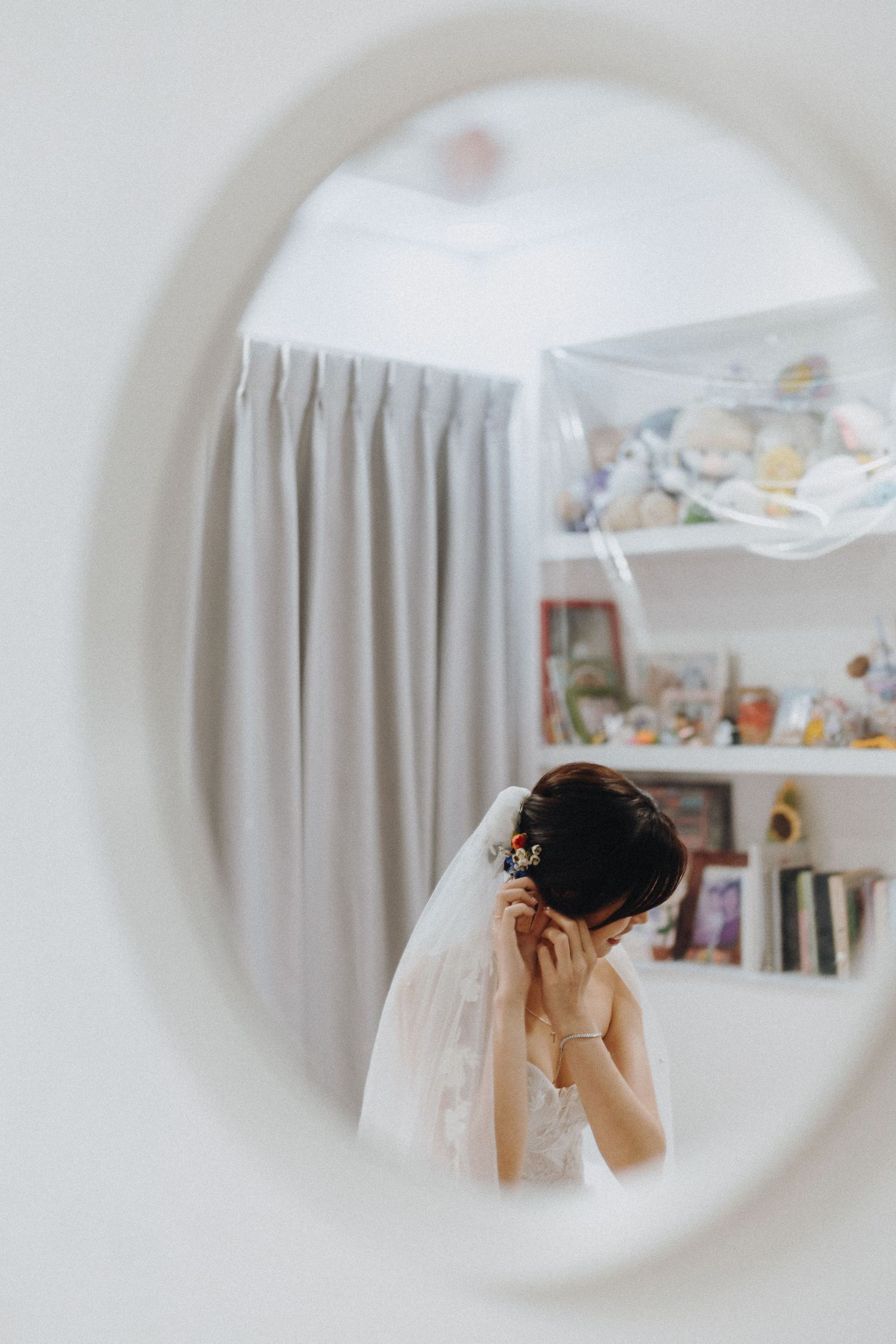 A bridal reflection in an oval mirror shows someone preparing for their wedding with delicate veil details.