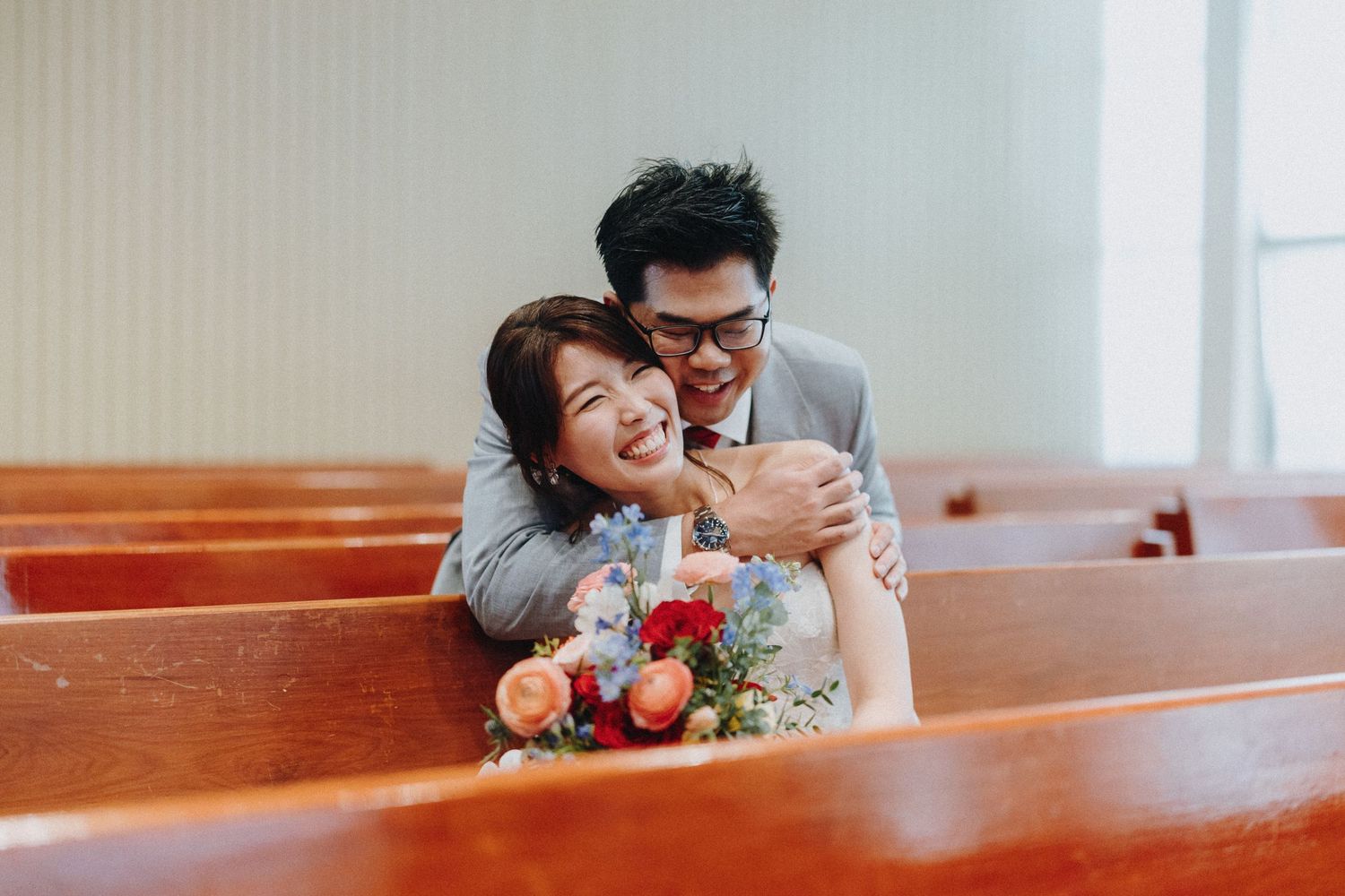 Wedding couple sharing an intimate moment on wooden church pews.