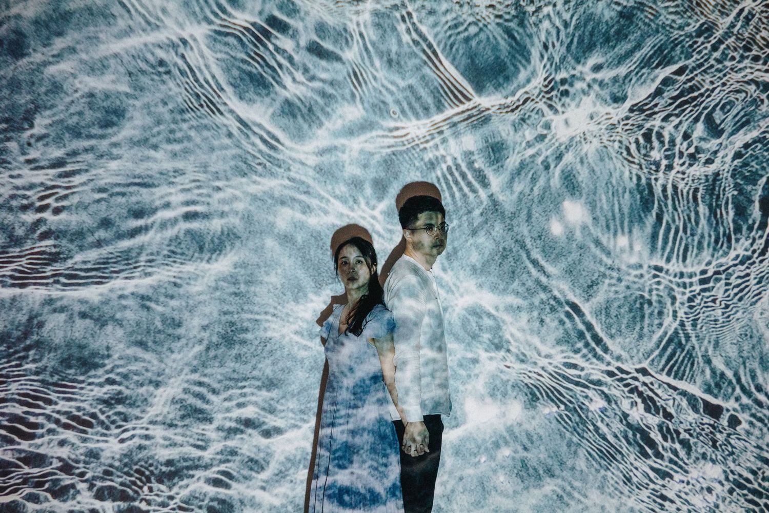 Creative double exposure portrait overlaying water ripples with couple in blue tones.
