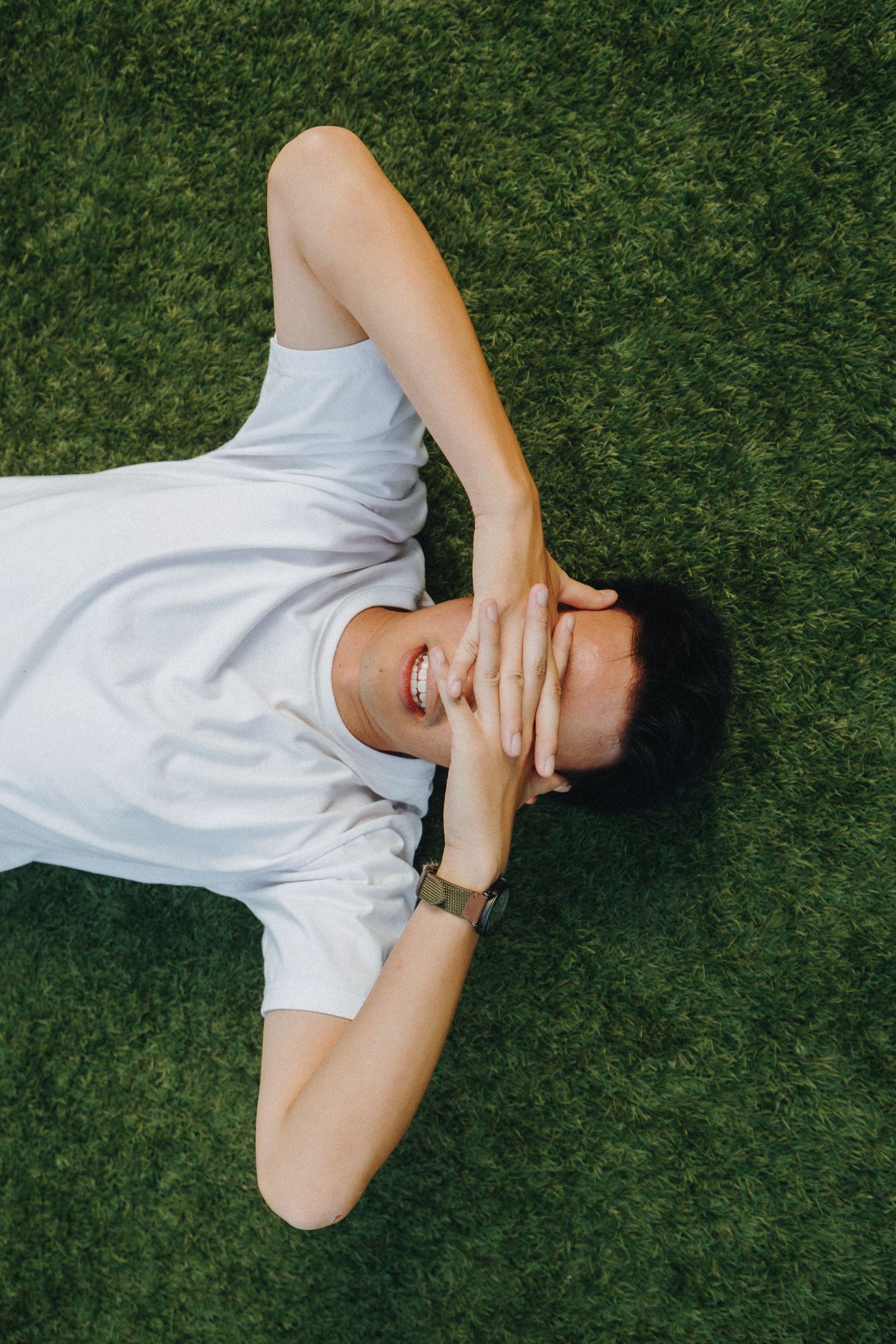 Person in white clothing lying on green grass in various artistic poses.