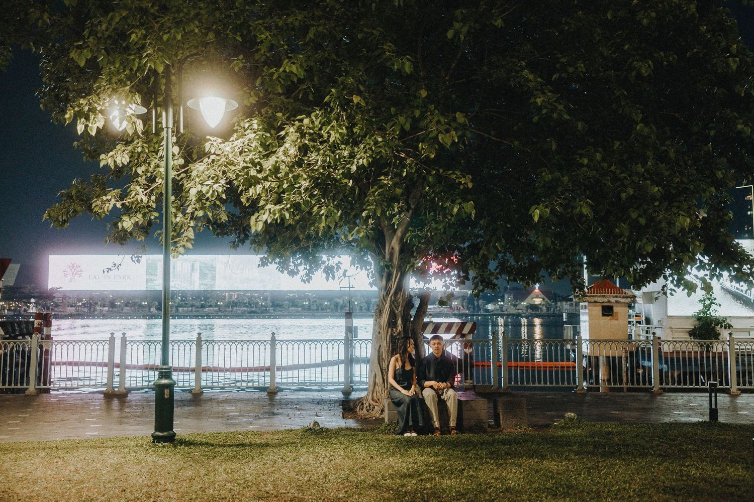 Panoramic nighttime waterfront scene with glowing lights reflecting on calm water.