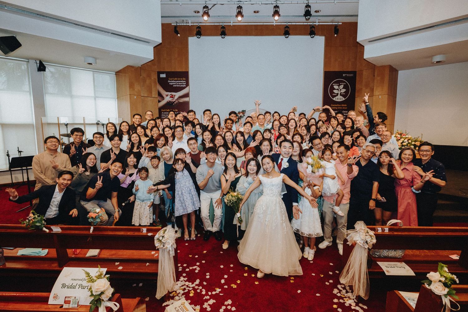 Wide shot of wedding guests seated in church pews during celebration.