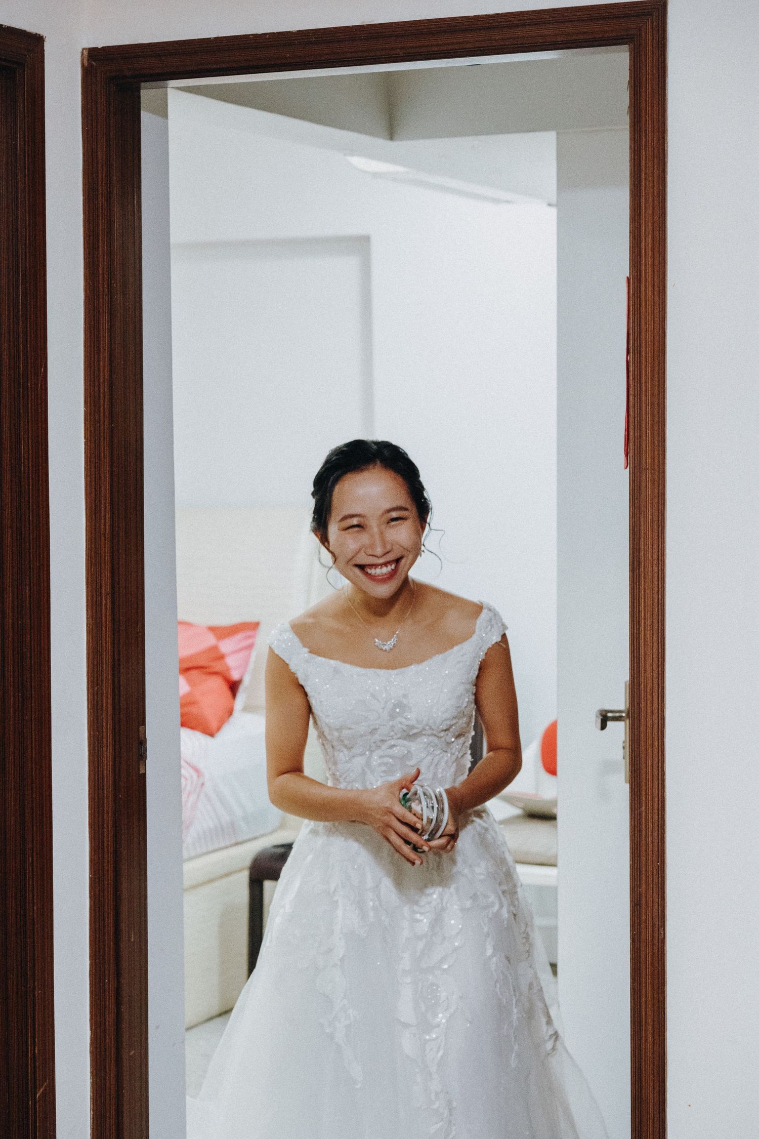 Bride in white wedding dress smiling and posing in front of mirrors.