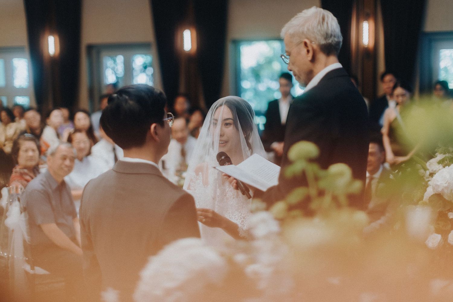 An indoor wedding ceremony with guests seated in rows watching the marriage proceedings at the altar.