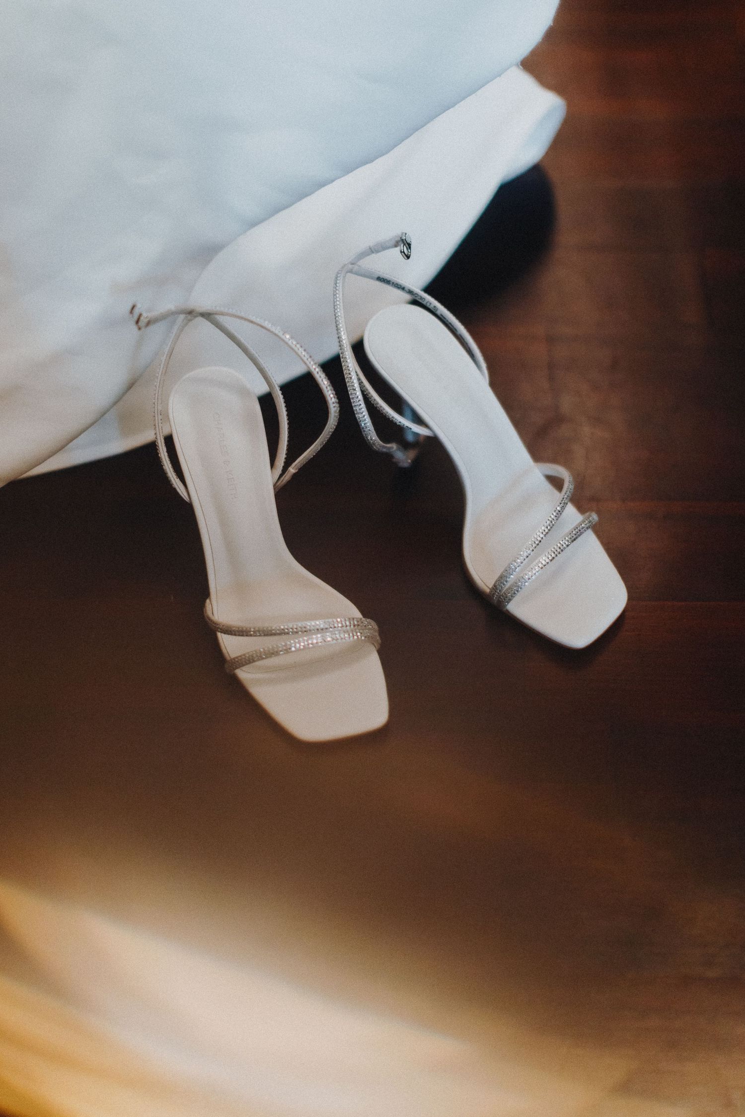 A close-up series of white wedding shoes against a dark wooden floor in various angles and compositions.