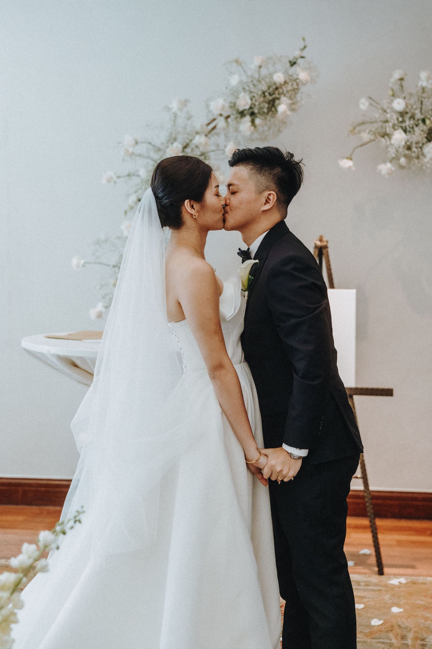 A tender wedding moment captured between newlyweds in front of floral decorations.